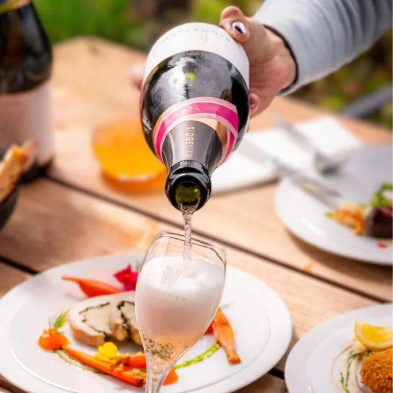 Fitzrovia Rosé, English Sparkling Wine being poured into a glass surrounded by a table of food at our restaurant