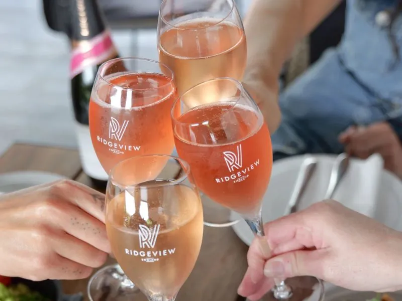 4 glasses of Fitzrovia Rosé, English Sparkling Wine toasting together over a table of food