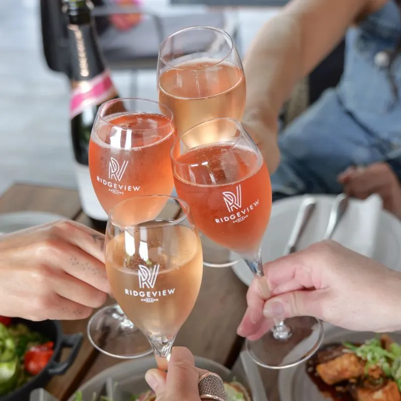 4 glasses of Fitzrovia Rosé, English Sparkling Wine toasting together over a table of food