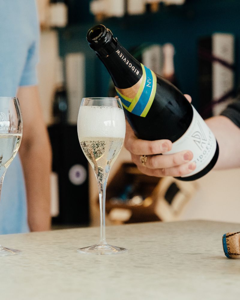 A bottle of Ridgeview Bloomsbury being poured into a glass in our shop